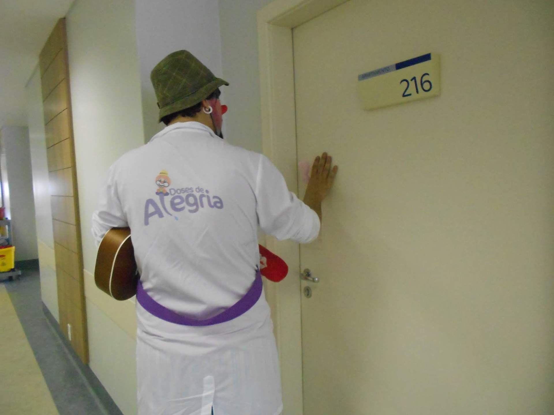 Doutor palhaço do Doses de Alegria entrando em quarto de hospital com violão